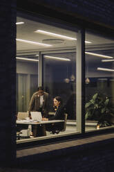 Reife Geschäftsfrau diskutiert mit einer Kollegin im Büro bei Nacht - MASF29529