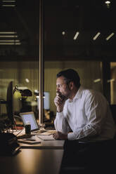 Mature businessman concentrating while working on laptop at work place - MASF29537