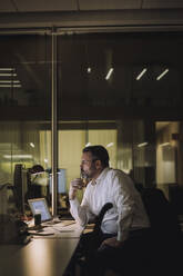 Mature businessman working on computer in work place at night - MASF29541