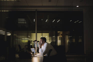 Businessman concentrating while working overtime in office at night - MASF29542