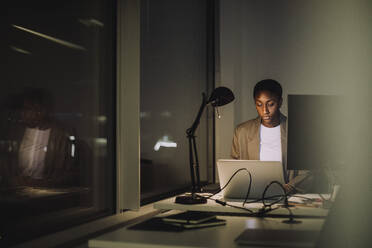 Ambitious businesswoman using laptop while working last minute in office - MASF29572