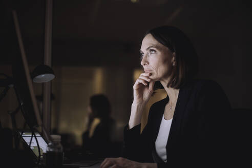 Reife Geschäftsfrau mit Hand am Kinn bei der Arbeit am Computer am Arbeitsplatz - MASF29578