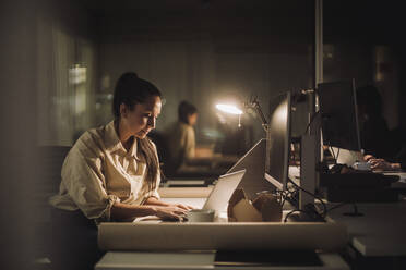 Geschäftsfrau konzentriert sich bei der Arbeit an einem Laptop im Büro - MASF29590