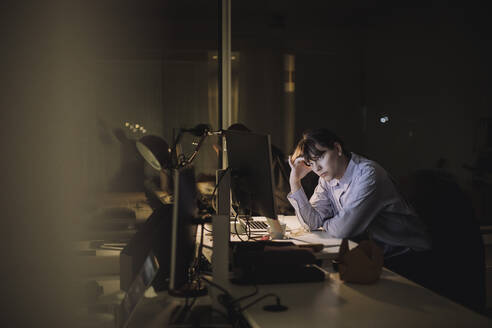 Müde junge Geschäftsfrau arbeitet am Schreibtisch im Büro - MASF29600