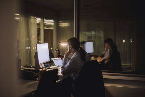 Junge Geschäftsfrau arbeitet am Computer spätabends am Arbeitsplatz - MASF29602