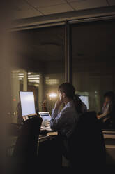 Young businesswoman working on computer late night in office - MASF29603