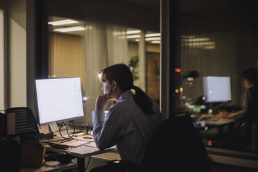 Junge Geschäftsfrau konzentriert sich bei der Arbeit am Computer im Büro bei Nacht - MASF29604