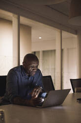 Mature businessman working late on laptop in office at night - MASF29612