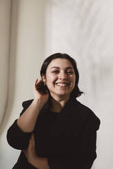 Portrait of smiling woman with hand in hair at studio - MASF29716