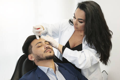 Dermatologe bei der Botox-Behandlung eines Patienten in einer Schönheitsklinik - MTBF01207