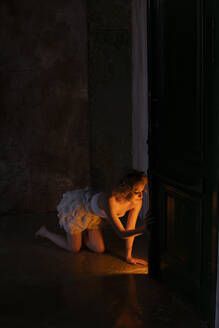 Beleuchtete junge Frau kniend im Dunkeln - SSGF00649