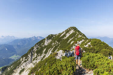 Frau mit Rucksack wandert auf einem Berg an einem sonnigen Tag - FOF13108