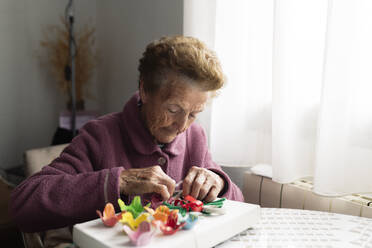 Ältere Frau beim Basteln am Esstisch sitzend - JCCMF06022