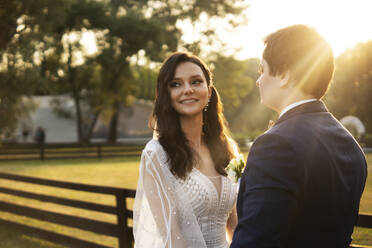 Smiling bride standing with groom on sunny day - SSGF00665