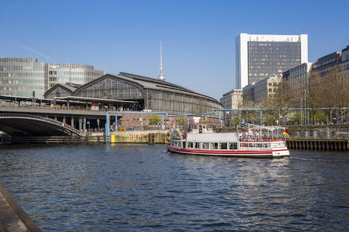 Germany, Berlin, Tourboat sailing along river Spree with Berlin Friedrichstrasse Station and Berlin Television Tower in background - MAMF02136