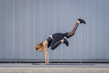 Woman balancing on hands exercising in front of wall - STSF03168