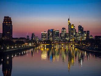 Germany, Hesse, Frankfurt, River Main canal at dusk with bridge and downtown skyscrapers in background - AMF09479