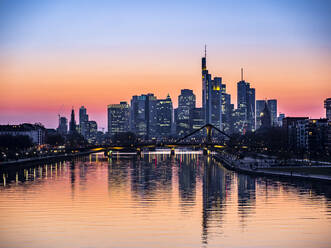 Germany, Hesse, Frankfurt, River Main canal at dusk with bridge and downtown skyscrapers in background - AMF09482