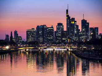 Germany, Hesse, Frankfurt, River Main canal at dusk with bridge and downtown skyscrapers in background - AMF09483