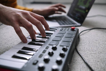 Hands of freelancer using laptop and piano in home studio - ASGF02256