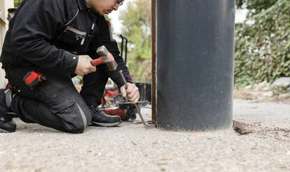 Bauarbeiter mit Hammer bei der Arbeit an einem Metallpfeiler - JCCMF06026