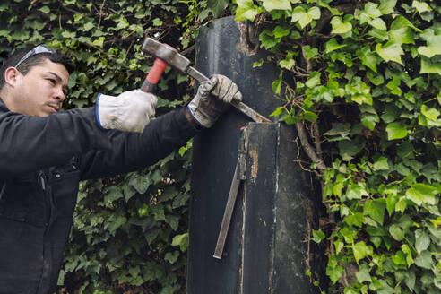 Construction worker with hammer working on metal gate - JCCMF06028