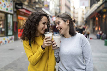 Glückliche Freunde, die mit Einwegbechern Milchshakes genießen - WPEF05950