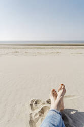 Woman sitting on sand on sunny day at beach - CHPF00846