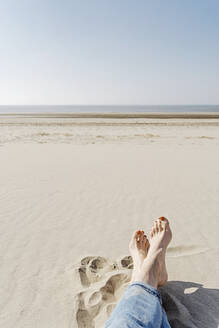 Frau sitzt auf Sand an einem sonnigen Tag am Strand - CHPF00846
