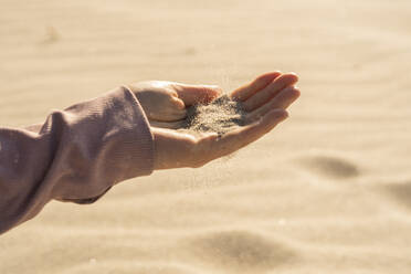 Woman with sand in hand on sunny day - SSGF00691