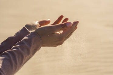 Junge Frau mit Sand in der Hand an einem sonnigen Tag - SSGF00692