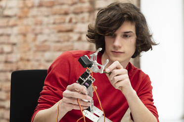 Teenage boy working on small robotic arm - DHEF00645