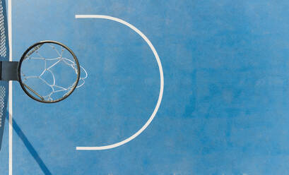 Top view of round basketball hoop with net placed on colorful sports ground with blue surface on sunny summer day - ADSF34515