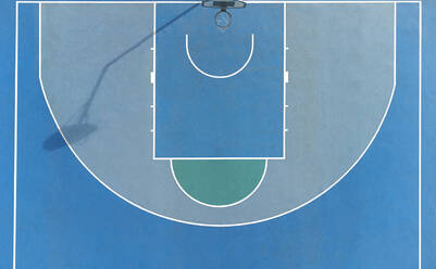 Top view of basketball hoop placed on sports ground with blue surface and lines on sunny summer day in city - ADSF34516