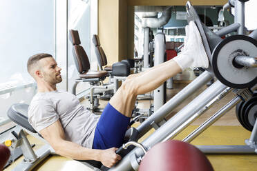 Junger Mann beim Training an der Beinpresse im Fitnessstudio - IFRF01567