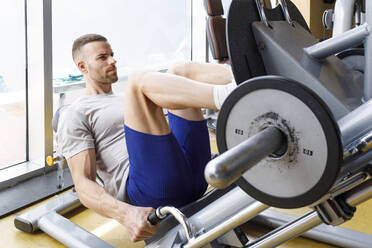 Man exercising in gymnasium, using parallel bars, in L-sit hold stock photo