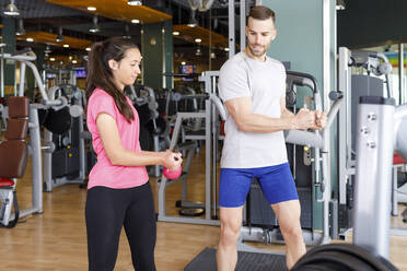 Ausbilderin führt Frau beim Training mit Kettlebell im Fitnessstudio an - IFRF01575