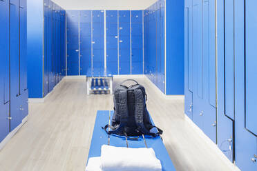 Backpack on bench in empty locker room at gym - IFRF01597