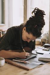 Woman carving on clay plate with hand tool at workshop - SSGF00695