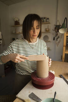 Craftsperson giving shape to clay pot at workshop - SSGF00698