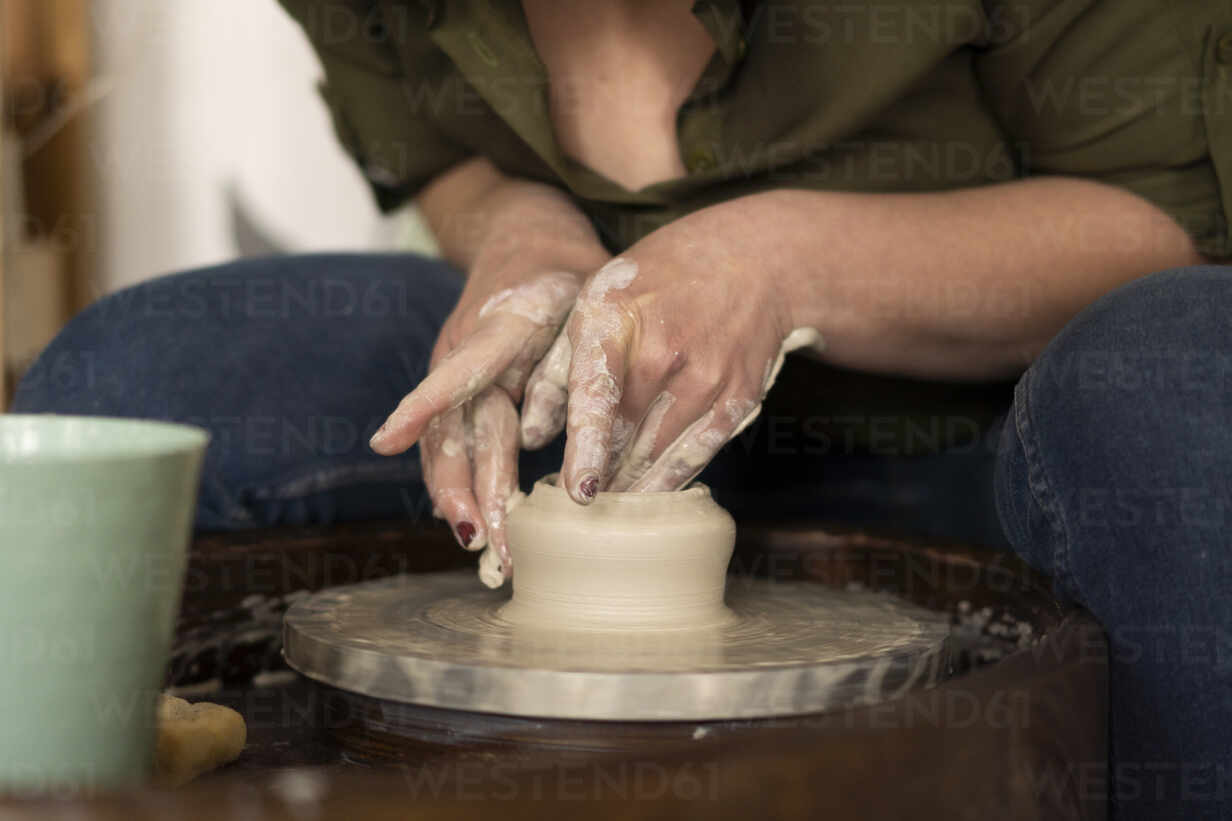 Female potter molding clay on pottery wheel in workshop stock photo