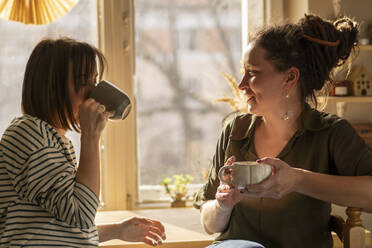 Woman talking with coworker drinking coffee in workshop - SSGF00714