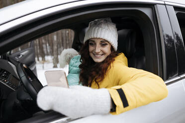 Happy woman taking selfie through mobile phone sitting with dog in car - SIF00063