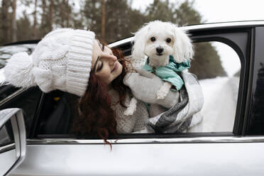 Lächelnde Frau mit Hund, die sich aus dem Autofenster lehnt - SIF00072