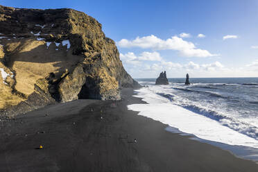 Luftaufnahme von Menschen in Reynisfjara, einem schwarzen Sandstrand an der Küste Islands. - AAEF14400