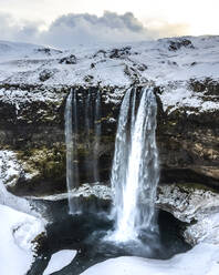 Aerial view of Seljalandsfoss, a beautiful waterfall with snow in wintertime in Iceland. - AAEF14403