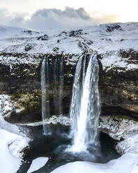 Luftaufnahme des Seljalandsfoss, eines wunderschönen Wasserfalls mit Schnee im Winter in Island. - AAEF14403