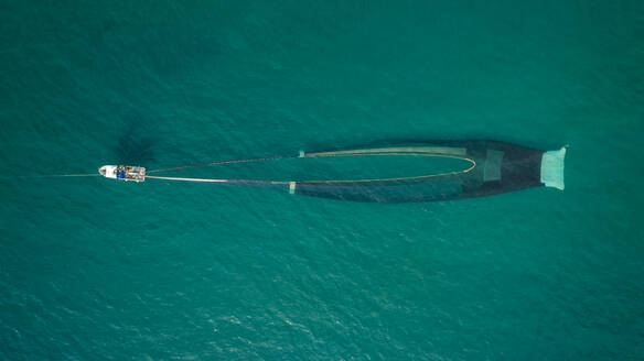 Luftaufnahme eines Motorboots beim Fischen mit einem Netz in El Golfo, Mittelmeer, Girona, Spanien. - AAEF14430