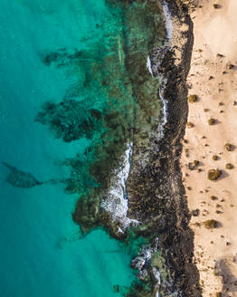 Luftaufnahme des schwarzen Sandstrands entlang der Küste nach der Wüste im Naturpark Corralejo, Fuerteventura, Kanarische Inseln, Spanien. - AAEF14475