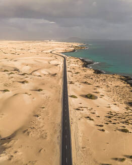 Luftaufnahme einer Straße entlang der Küste durch den Naturpark Sanddünen in Corralejo, Fuerteventura, Kanarische Inseln, Spanien. - AAEF14476